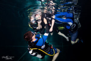 Mehrere Personen beim Inklusionstauchen im Tauchturm Seiersberg, begleitet von Tauchlehrer:innen, die unterstützend im Wasser helfen und Sicherheit geben.